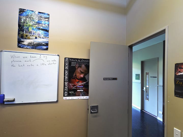 Corridor with posters on wall and door labelled with room name