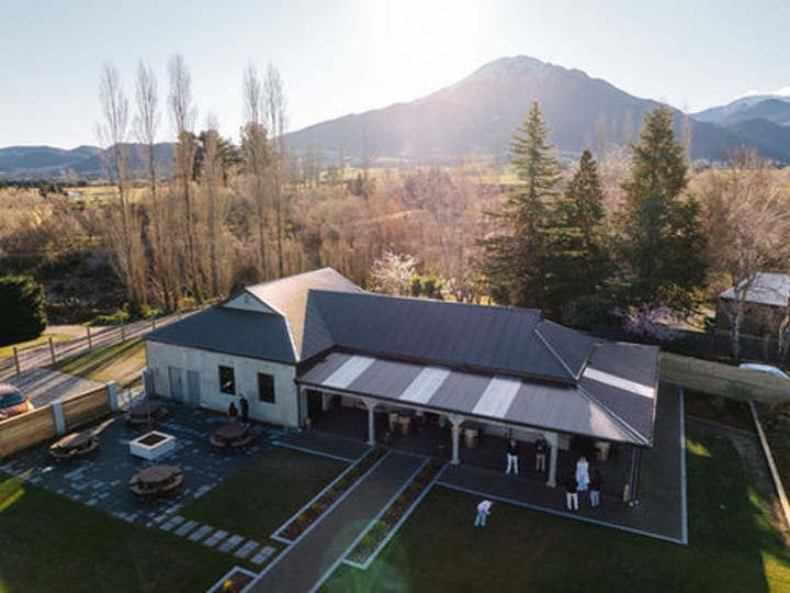 Aerial view of venue buildings, lawn, outdoor seating, and surrounding trees with mountain