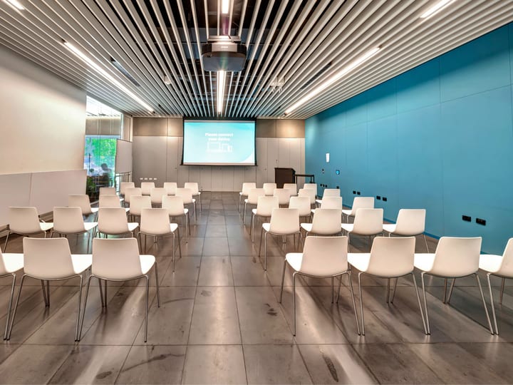 Conference room with white chairs in theatre layout and projected screen