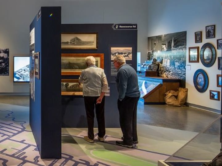 Museum exhibition hall with blue display panels, photographs, and map floor