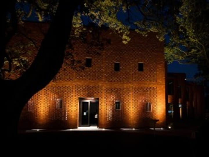 Red-brick college building illuminated at night from front entrance