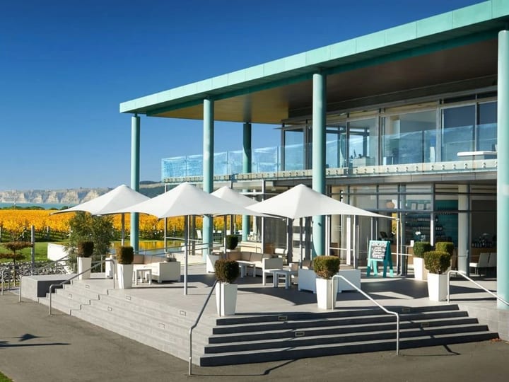 Winery exterior with an elephant sculpture, autumn vineyard rows and coastal cliffs beyond