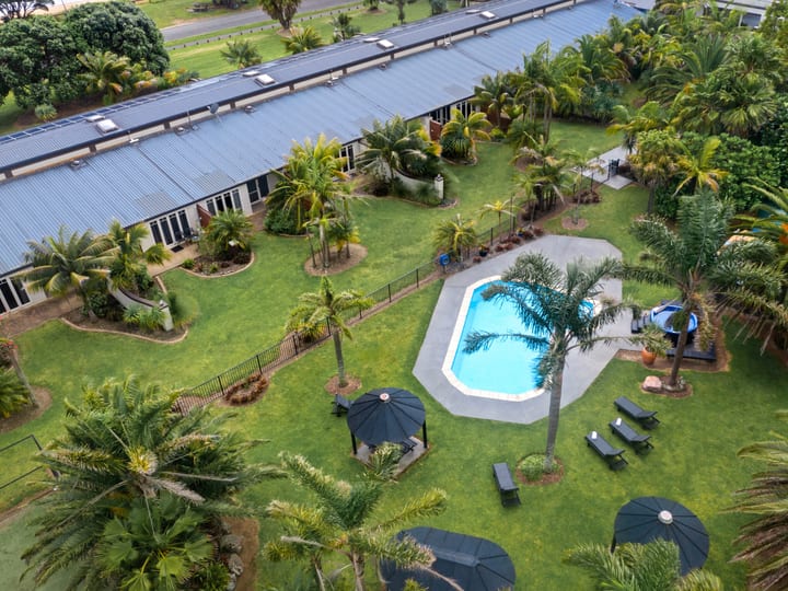 Aerial view of resort buildings, lawn, pool, and tropical plantings