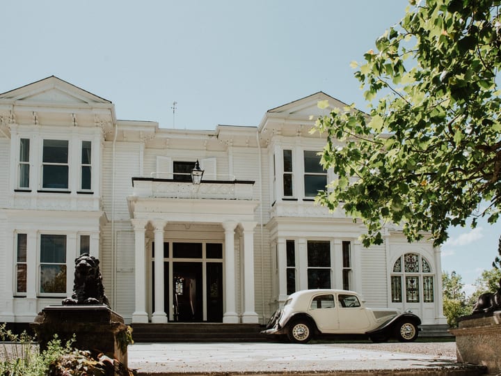 White two-storey villa facade with vintage car parked at entrance