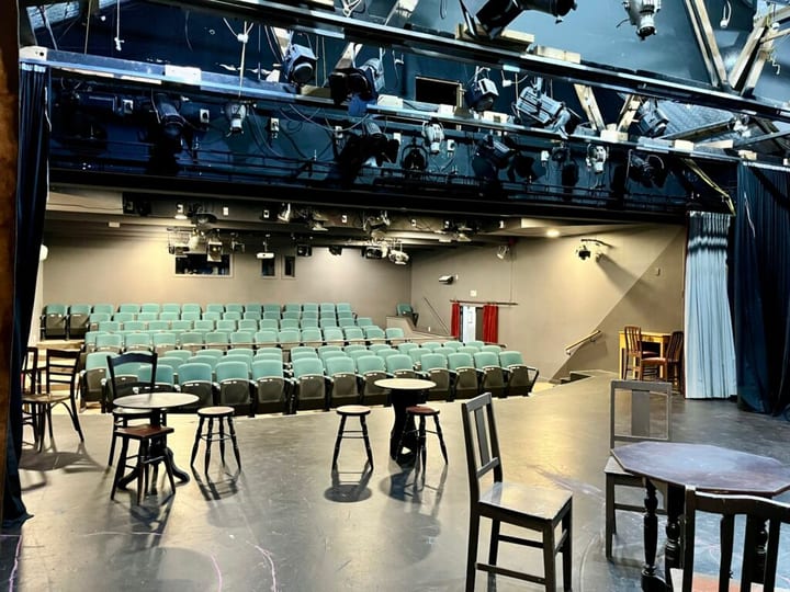 Theatre auditorium viewed from stage with tiered seating and stage lighting rigs