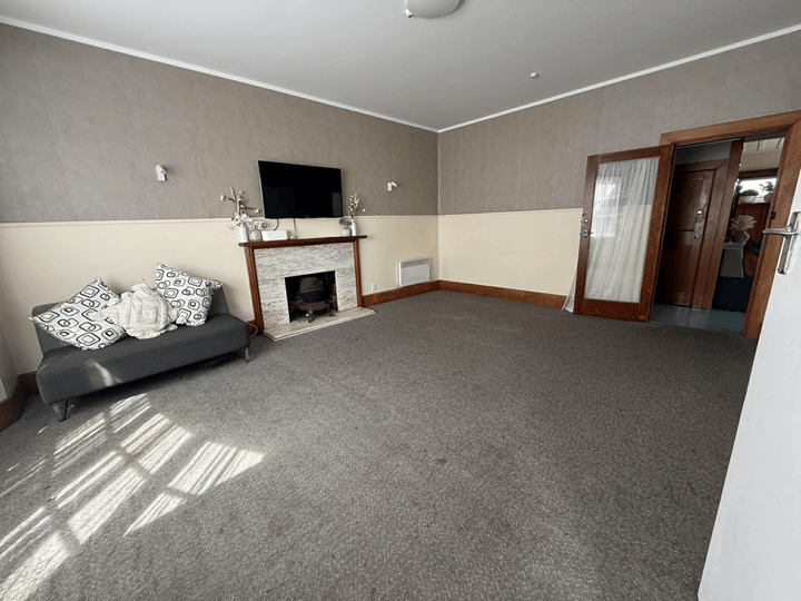 Carpeted lounge room with fireplace, sofa, and wall-mounted TV