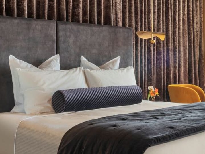Luxury hotel room with upholstered headboard, layered bedding and warm side lamps