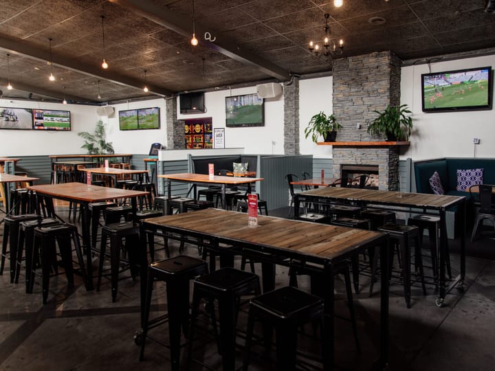 Outdoor courtyard with metal chairs and tables under pergola, venue signage on wall