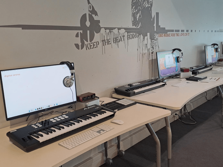 Music production room with keyboard controllers, monitors, and mural wall
