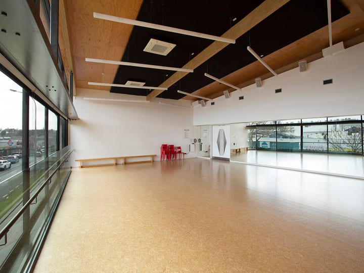 Foyer corridor with patterned carpet, posters on white walls, and staircase with timber handrail