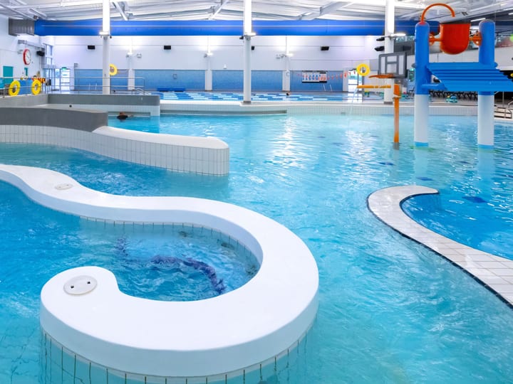 Indoor pool with curved water feature, lazy river and play equipment