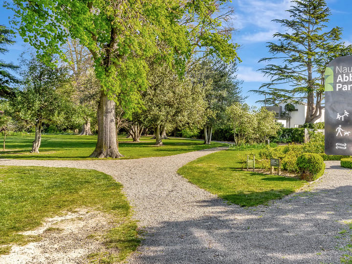 Park entrance with gravel path, park signage, and lawns