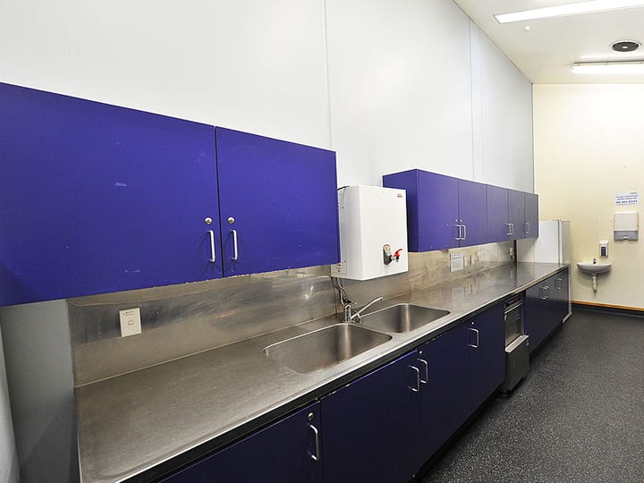 Kitchen servery with blue upper cabinetry and stainless steel benchtop