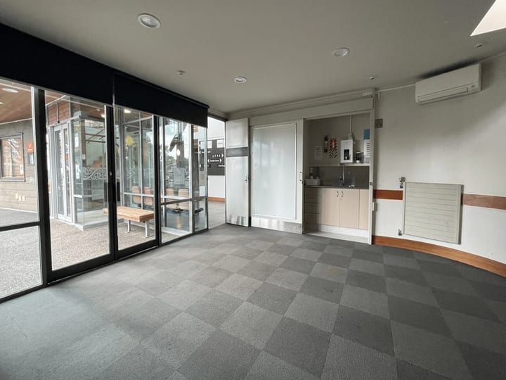 Small plain interior room with fluorescent lighting and window to outdoor deck