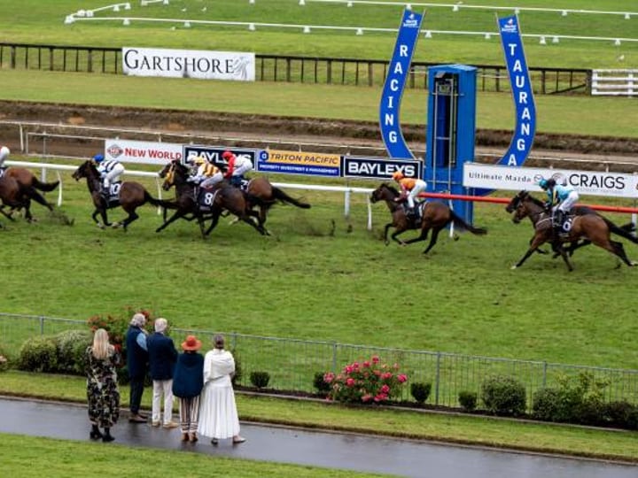 Horse race in progress on turf track with spectators watching from trackside