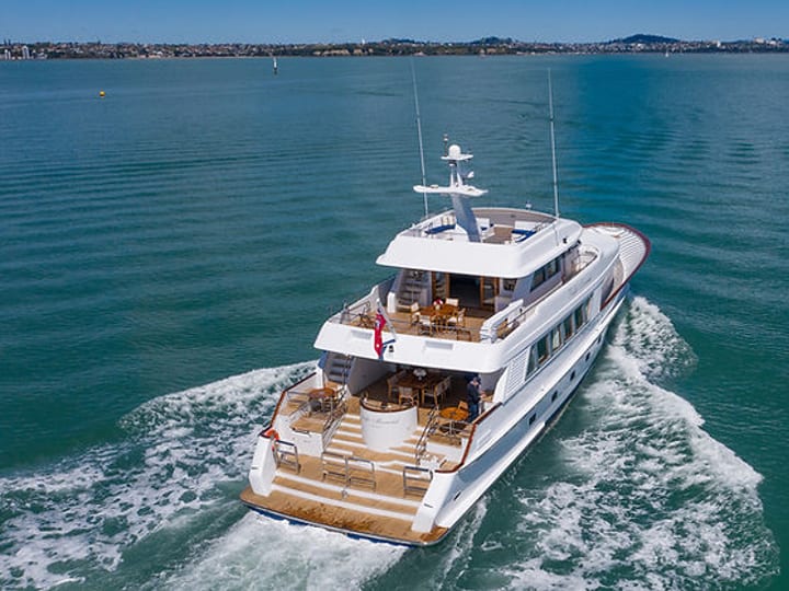 Large motor yacht underway in harbour with city skyline in background