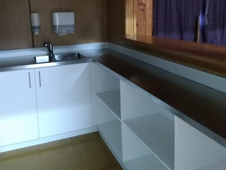 Timber-panelled bar servery area with stainless bench and pass-through window