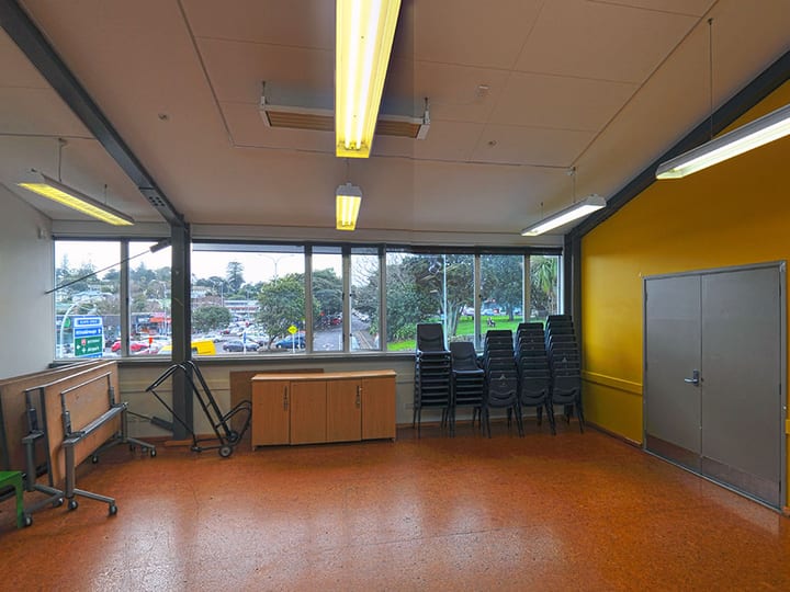 Plain room with yellow accent wall, stacked chairs, and strip lighting