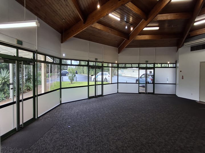 Hall with exposed timber roof beams and full-height glazed window walls