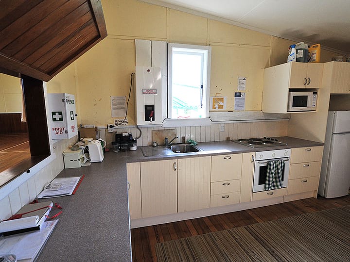 Cream-walled kitchen with L-shaped cabinetry, oven, and microwave under a low ceiling