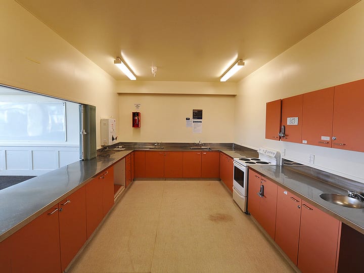Catering kitchen with orange cabinets and stainless steel benchtops