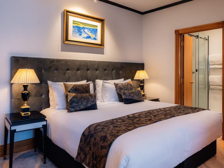 Hotel room with upholstered bedhead, bedside lamps, and ensuite doorway