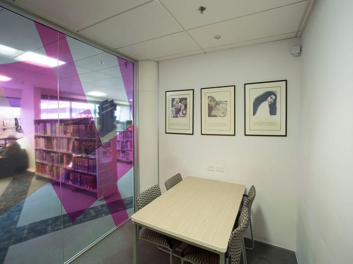 Small meeting room with timber table, chairs, and three framed artworks on wall