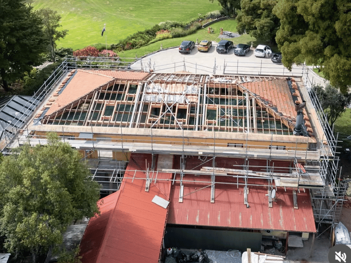 Building under roof renovation with scaffolding, aerial view