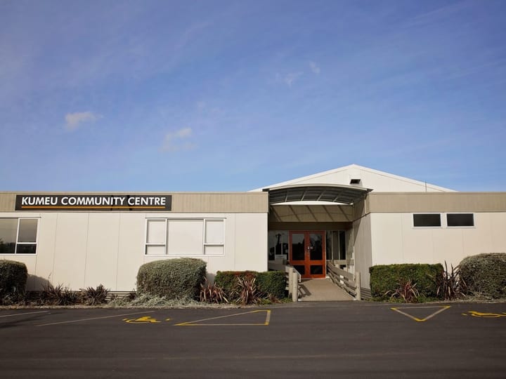 Single-storey community centre building with car park in foreground