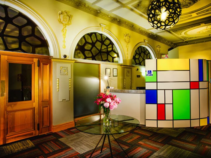 Heritage foyer with plaster arches and cornices, colourful geometric reception desk