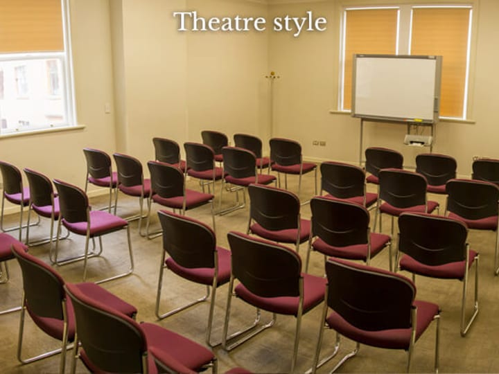 Meeting room with chairs in theatre-style layout and projector screen