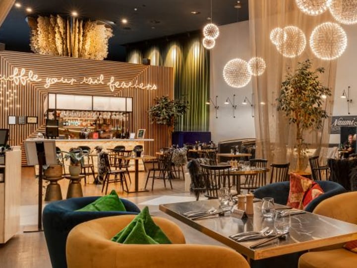 Contemporary hotel bar and restaurant with spherical pendant lights, timber slat screens, and coloured seating
