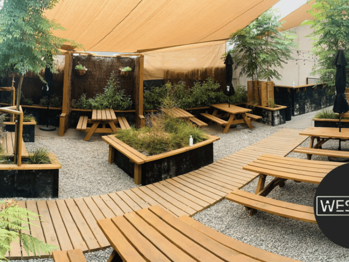 Outdoor beer garden with timber benches, raised planting beds and shade sails