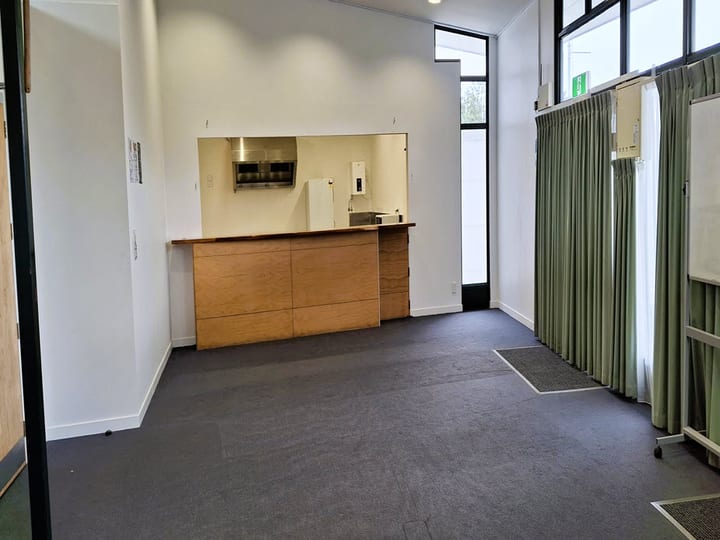 Small servery area with timber counter, kitchen hatch and green curtain room divider
