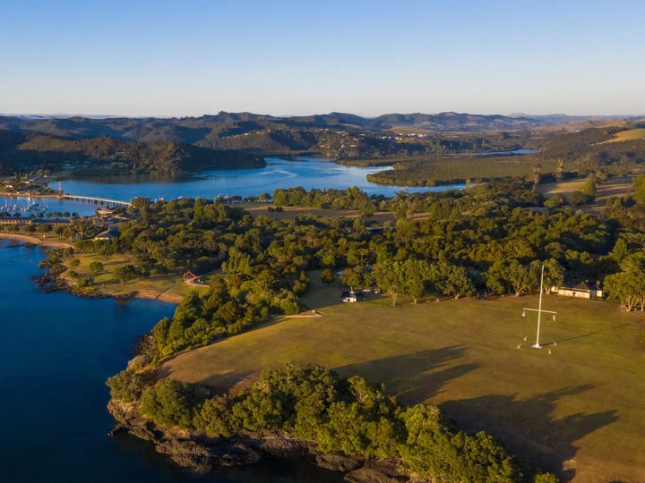 Aerial view of Waitangi Treaty Grounds on a bay peninsula surrounded by water and trees
