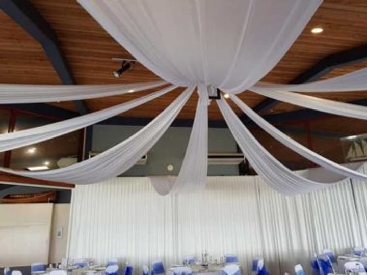Function room set for dining with draped white fabric ceiling and blue chair covers