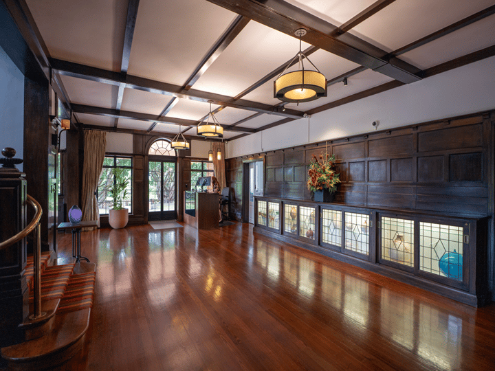 Grand hall with dark timber panelling, polished floor and stained glass cabinet