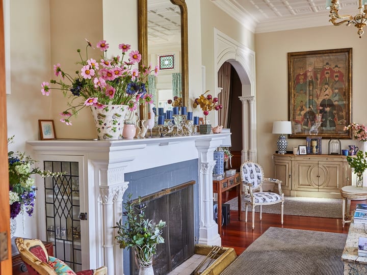 Heritage homestead interior lounge with ornate fireplace, flowers and period furnishings