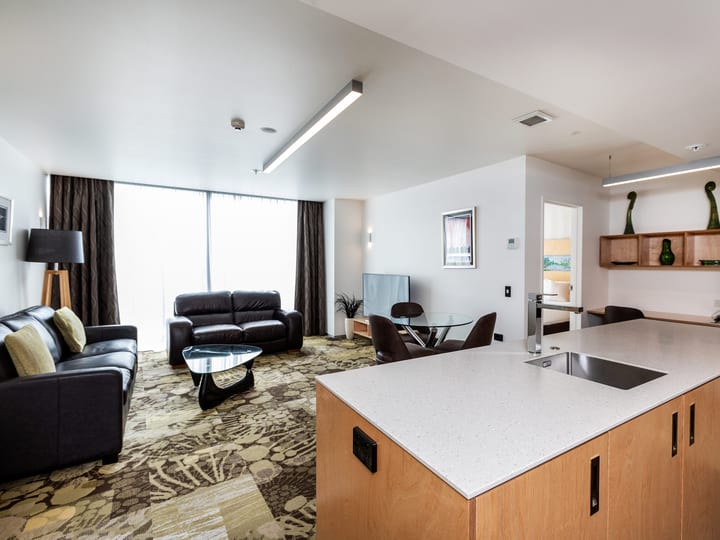 Hotel suite with lounge seating, kitchen island and patterned carpet