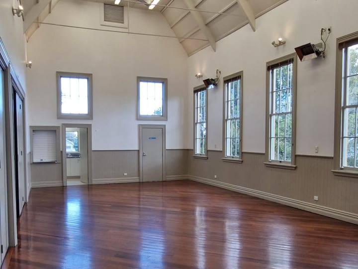 High-ceilinged hall interior with polished timber floor and tall windows