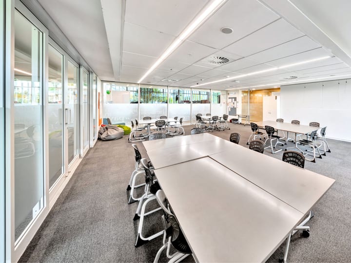 Flexible room with tables and chairs in open layout, whiteboard on wall