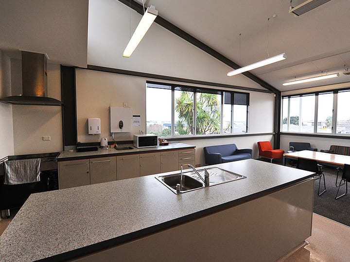 Kitchen area with island bench, sink, and seating area with large windows