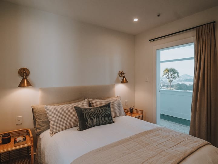Neutral-toned bedroom with wall sconces and glazed door to outdoor view