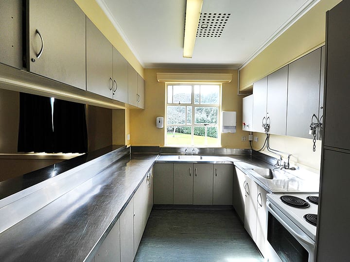 Catering kitchen with grey cabinets, stainless benches and window