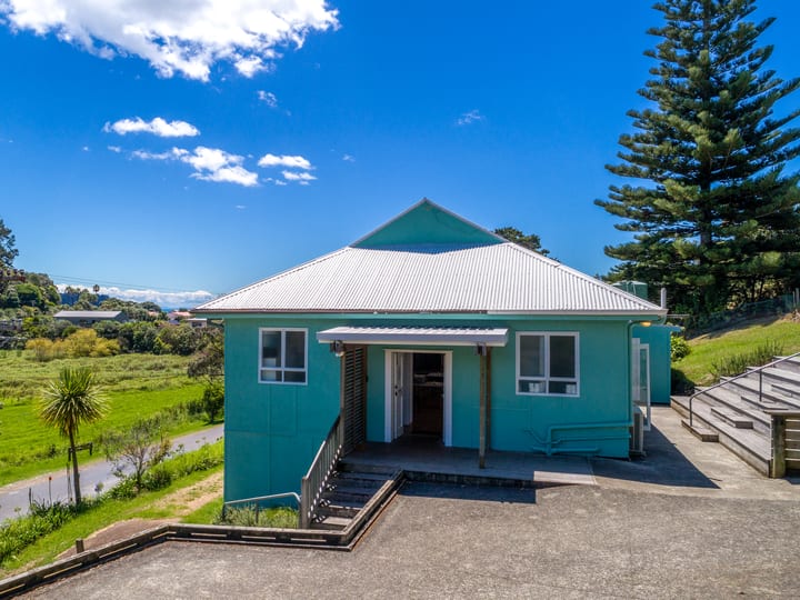 Aerial view of small teal-painted hall with corrugated iron roof on grassy site