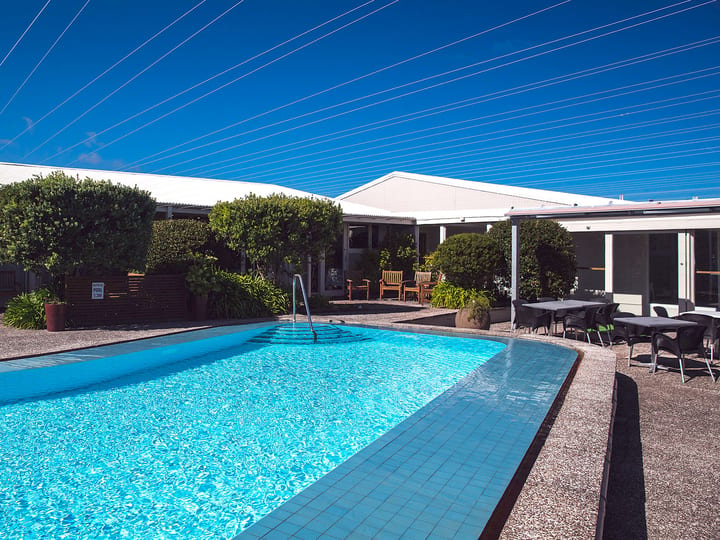 Outdoor swimming pool with garden and motel buildings surrounding it
