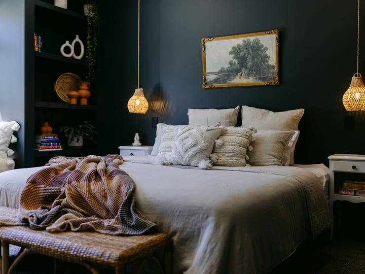 Styled bedroom with dark walls, pendant lights and framed artwork