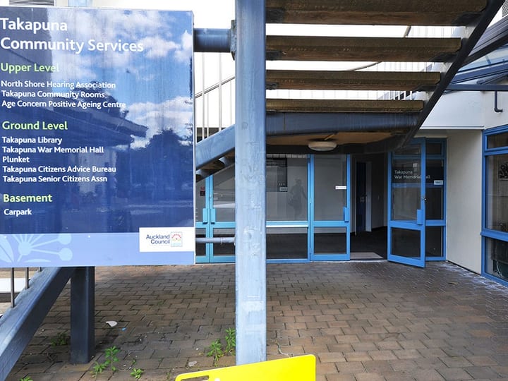 Building entrance with directory signboard listing tenants, glazed doors leading to hall beyond