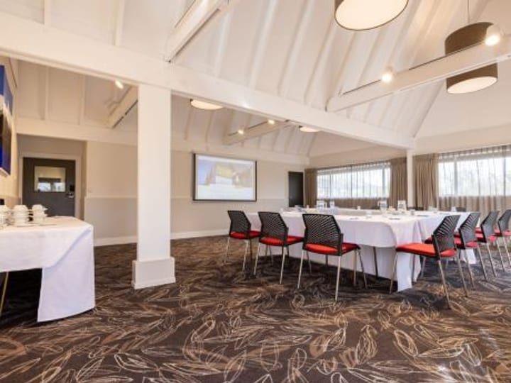 Conference room set in U-shape layout with projector screen and patterned carpet