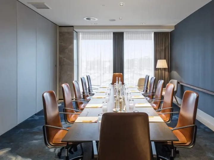 Hotel boardroom with long table, leather chairs, and large windows